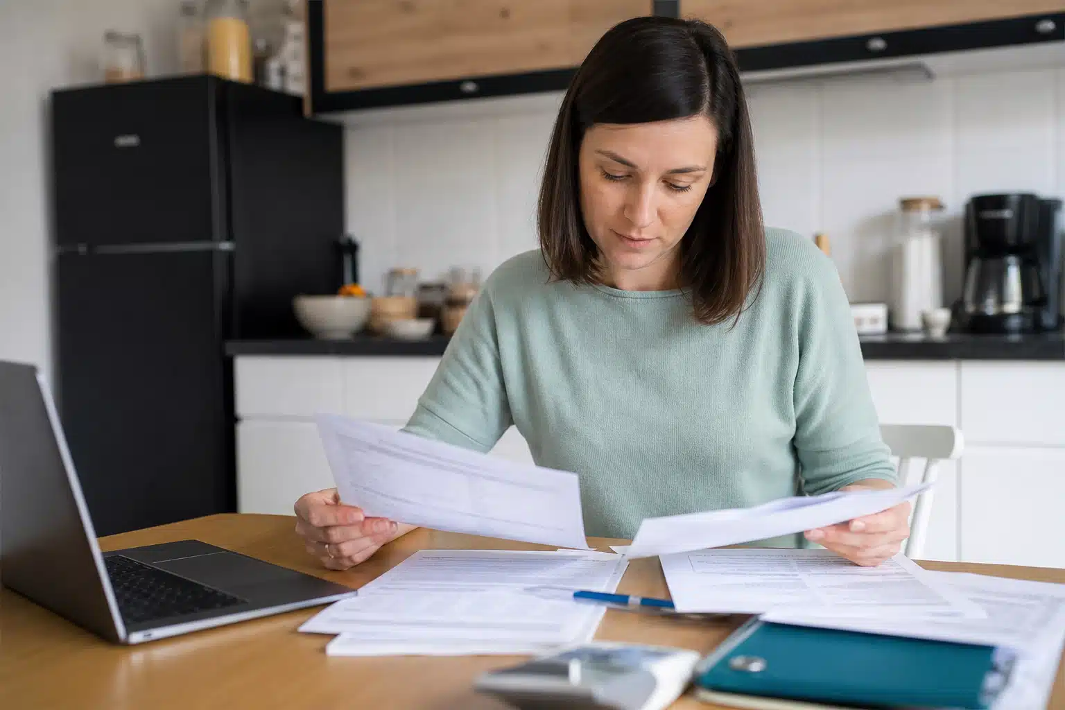Femme examinant des factures et documents à table